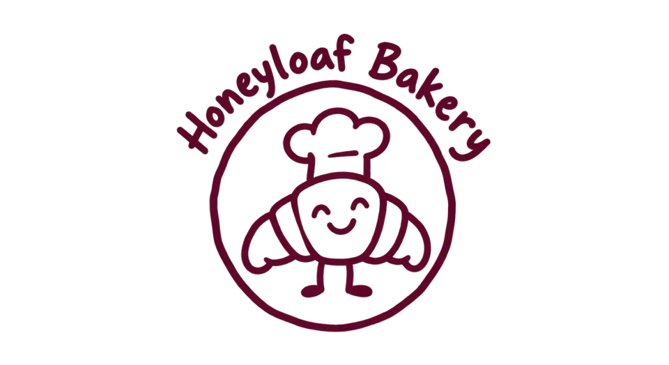 Honeyloaf Bakery mascot logo idea: The bakery’s name curves over a friendly croissant character, bringing the whole mark together like a personal bakery stamp.